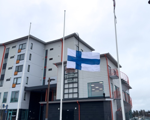 Suomen lippu puolitangossa kerrostalon pihalla