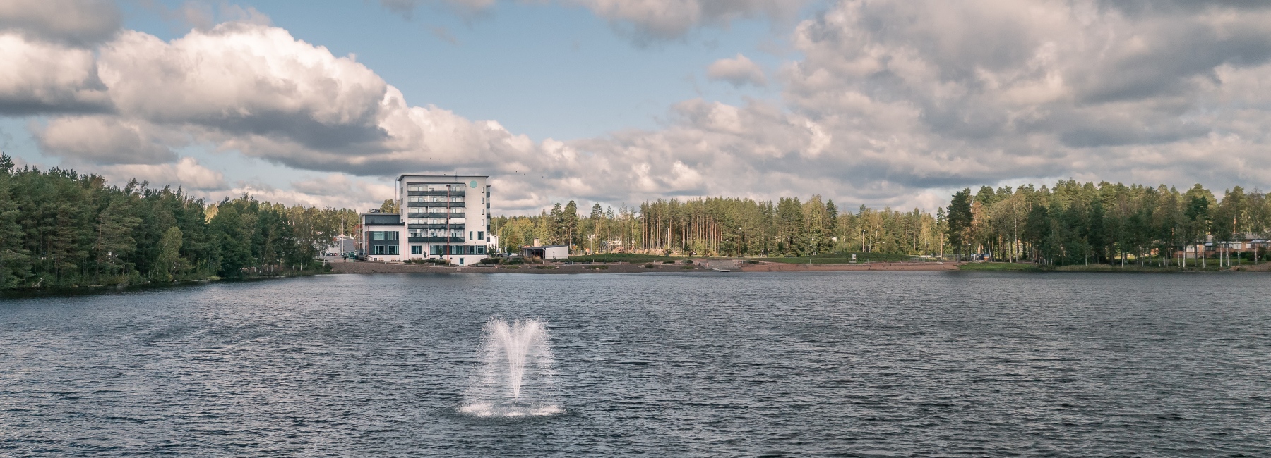 Kerrostalo järven rannalla, suihkulähde