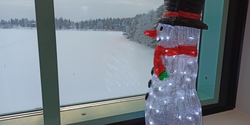 Lumiukkokoriste katsoo ikkunasta